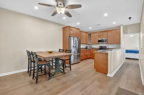 a kitchen with stainless steel appliances kitchen island granite countertop a table chairs and a refrigerator
