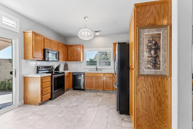 a kitchen with stainless steel appliances granite countertop a refrigerator a stove a sink a dining table and chairs with wooden floor