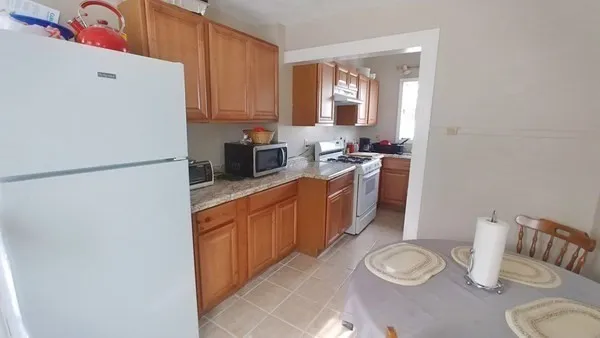 a kitchen with stainless steel appliances a refrigerator a sink a stove a dining table and chairs