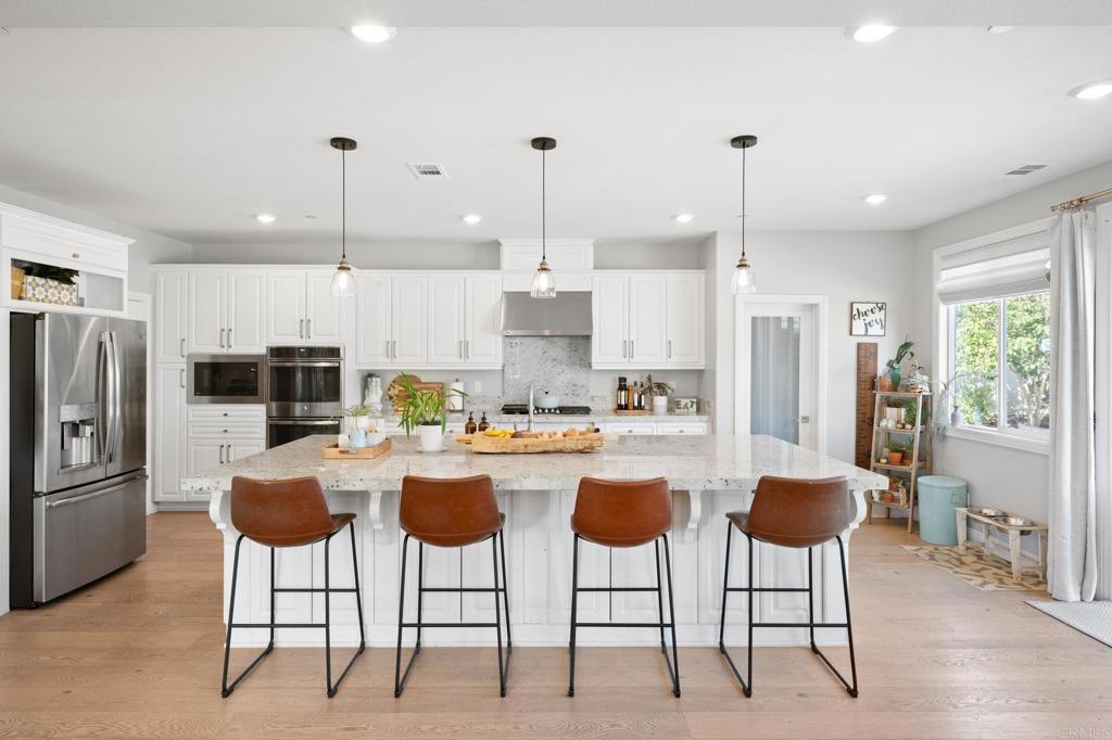 1211 Tesoro Place Vista, CA 92081 - Photo 13 of 57 a kitchen with stainless steel appliances kitchen island granite countertop a refrigerator a stove a kitchen island with chairs and cabinets
