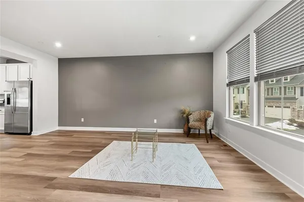 a living room with stainless steel appliances kitchen island a stove a refrigerator cabinets and wooden floor