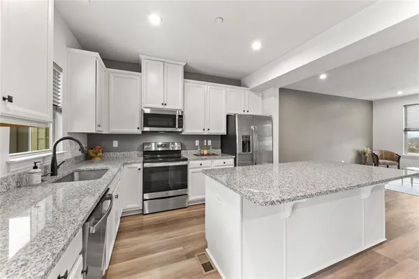 a kitchen with stainless steel appliances granite countertop a stove a refrigerator and a microwave