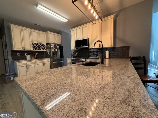 a kitchen with kitchen island granite countertop a sink a counter top space and cabinets