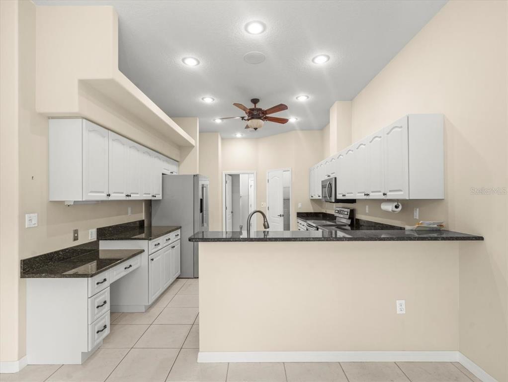 9037 Penelope Drive Weeki Wachee, FL 34613 - Photo 17 of 60 a large kitchen with granite countertop a sink stainless steel appliances and white cabinets