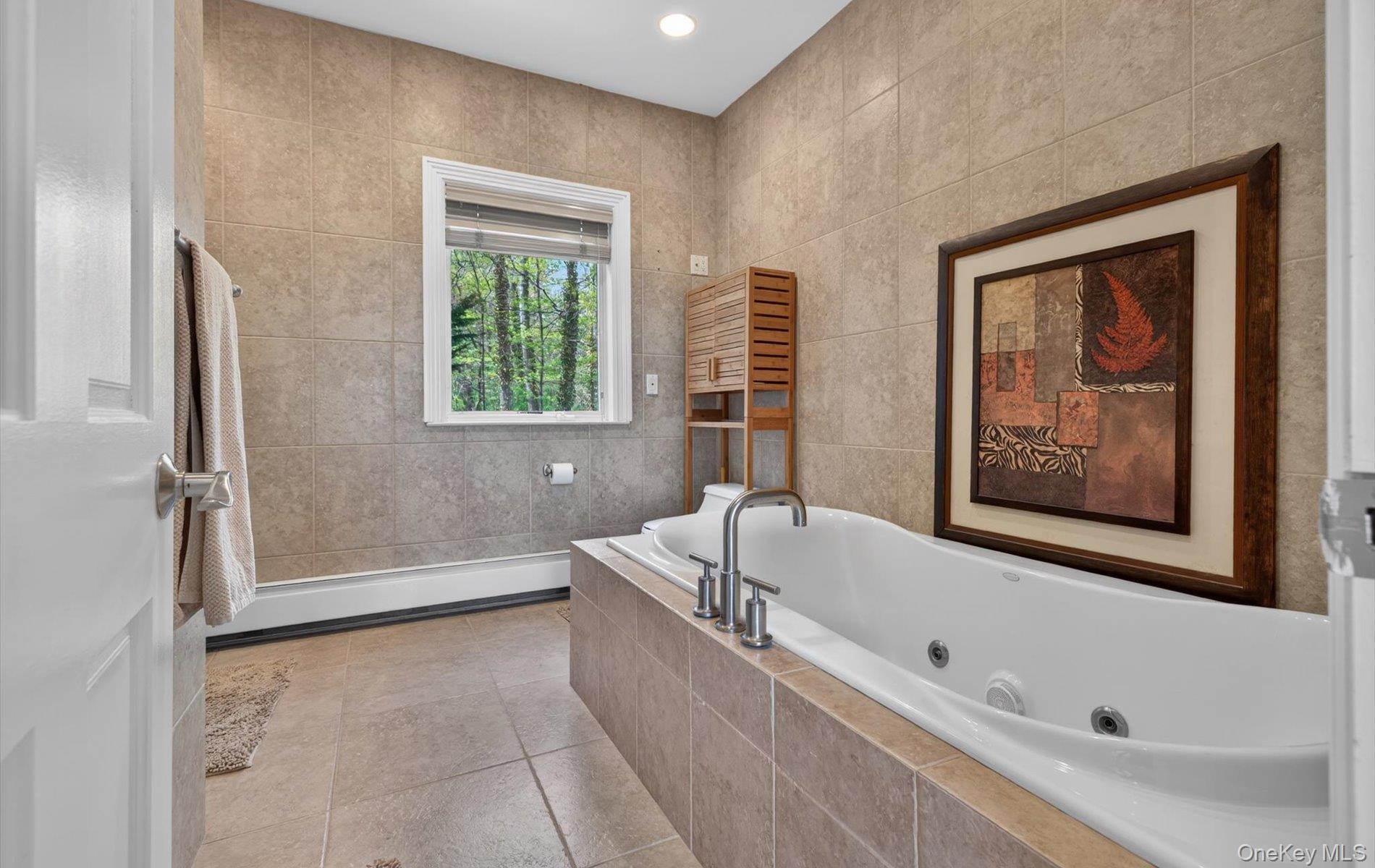 16 East Slope Road Bayville, NY 11709 - Photo 29 of 48 Spacious bathroom featuring an integrated soaking tub, floor-to-ceiling tile, and a prominent window