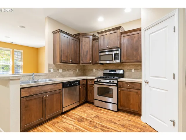 a kitchen with stainless steel appliances granite countertop a stove a sink and a microwave