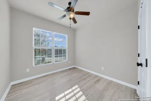 a view of an empty room with a window and wooden floor