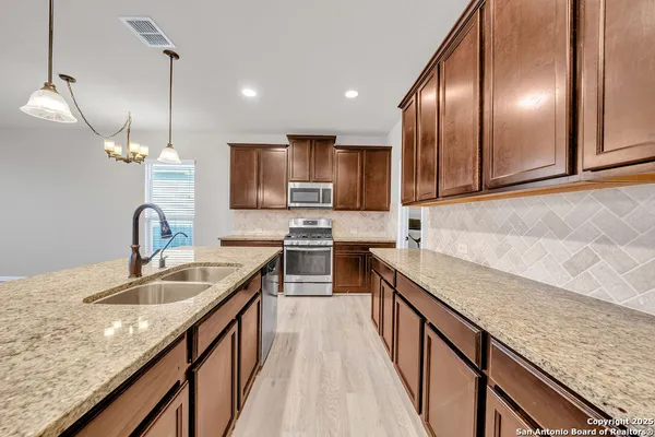 a kitchen with stainless steel appliances granite countertop sink stove top oven and refrigerator