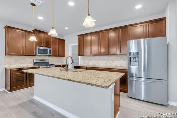 a kitchen with kitchen island granite countertop stainless steel appliances and refrigerator