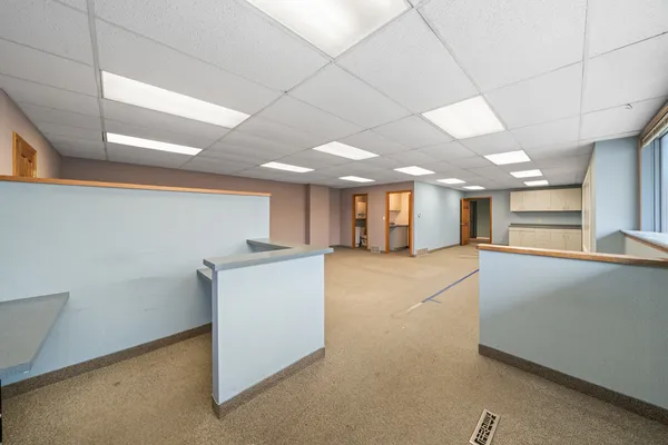 a view of an empty room with kitchen and window