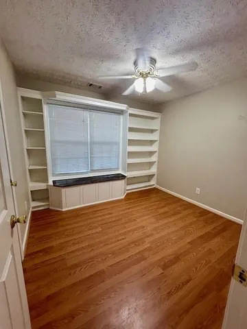 an empty room with wooden floor closet and windows