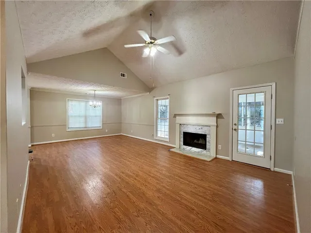 an empty room with wooden floor fireplace and windows