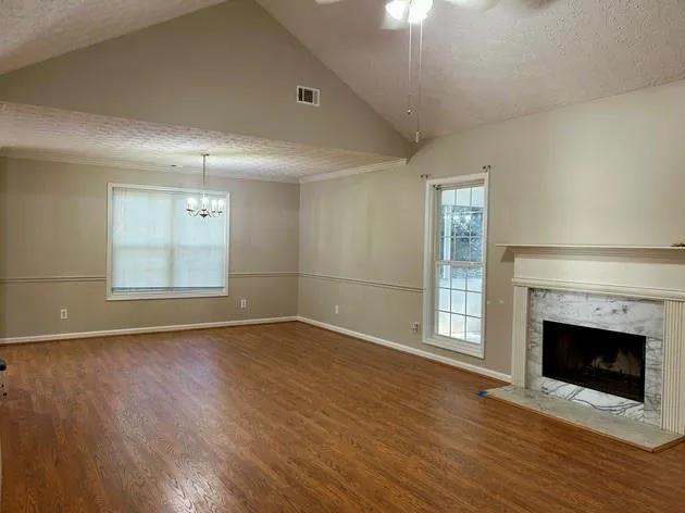 an empty room with wooden floor fireplace and windows
