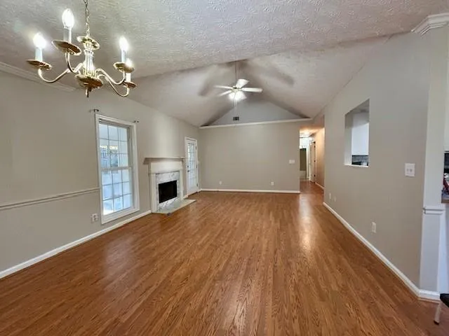 a view of an empty room with wooden floor and a ceiling fan
