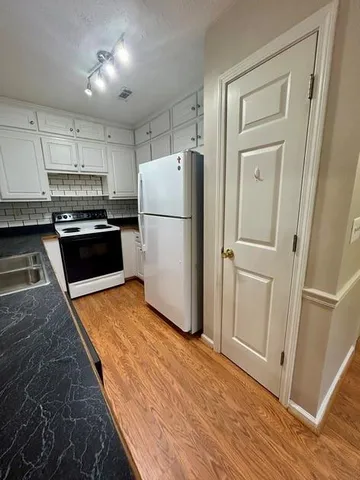 a kitchen with a refrigerator a stove top oven and wooden floor