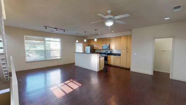 a view of an empty room with kitchen appliances and wooden floor