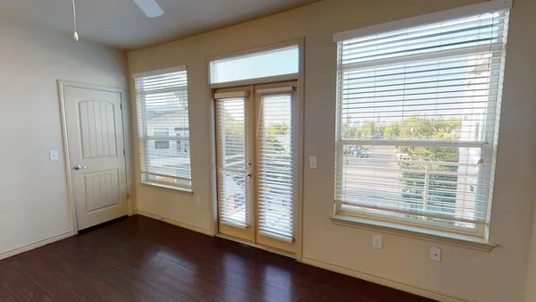 a view of an empty room with wooden floor and a window
