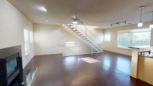 a view of an empty room with wooden floor fireplace and a window