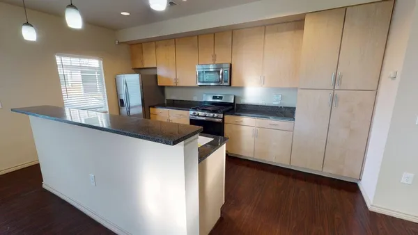 a kitchen with stainless steel appliances granite countertop a sink a stove a microwave a refrigerator a cabinets and wooden floor