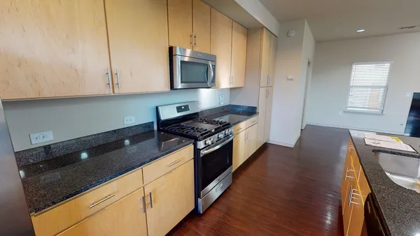 a kitchen with granite countertop a stove a sink and a microwave