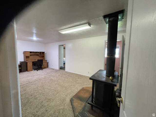 438 East Main Street Elsinore, UT 84724 - Photo 23 of 43 Spacious sitting room are of massive Primary Suite. Wood-burning stove with a stone hearth, neutral carpeting, white painted walls, and overhead fluorescent lighting