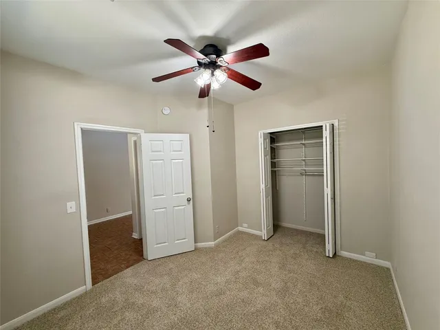 an empty room with closet and a ceiling fan