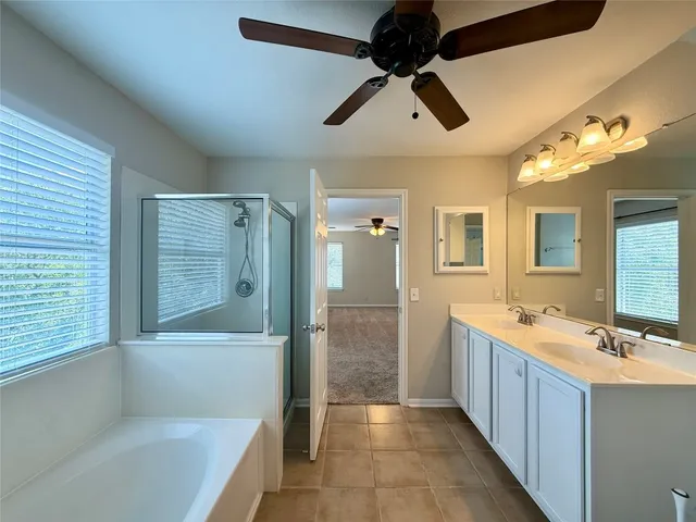 a bathroom with a double vanity sink a large mirror and a bathtub
