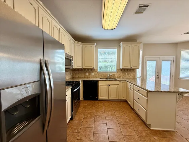 a large kitchen with stainless steel appliances granite countertop a stove a sink and a refrigerator