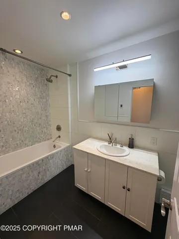 a bathroom with a double vanity sink and mirror with bathtub