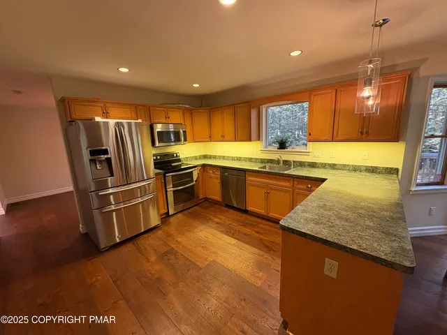 a kitchen with stainless steel appliances granite countertop a sink counter space cabinets and wooden floor