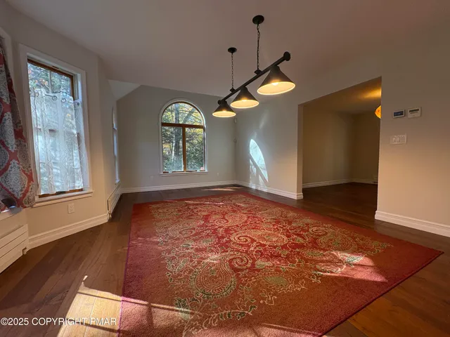 a view of an empty room with window and wooden floor