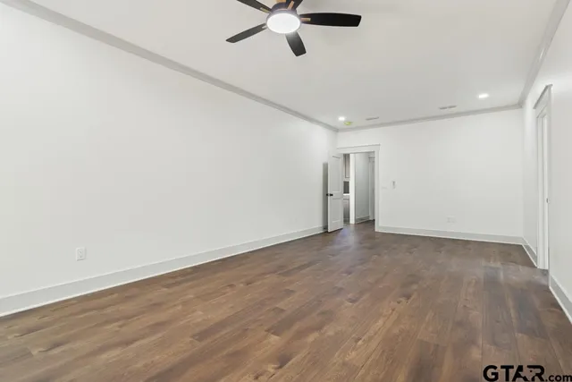 an empty room with wooden floor and a ceiling fan