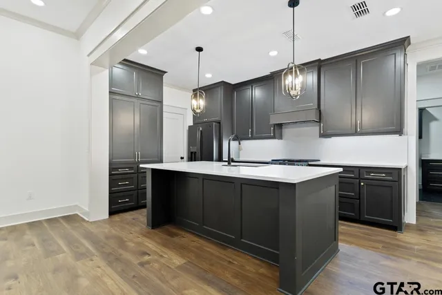a large kitchen with granite countertop a refrigerator and a sink