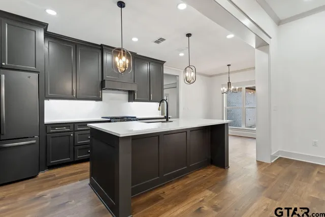 a kitchen with stainless steel appliances granite countertop a refrigerator a sink and a stove