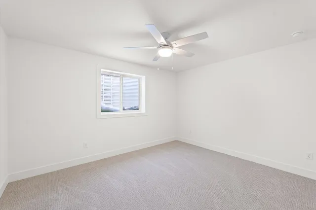 an empty room with a window and ceiling fan
