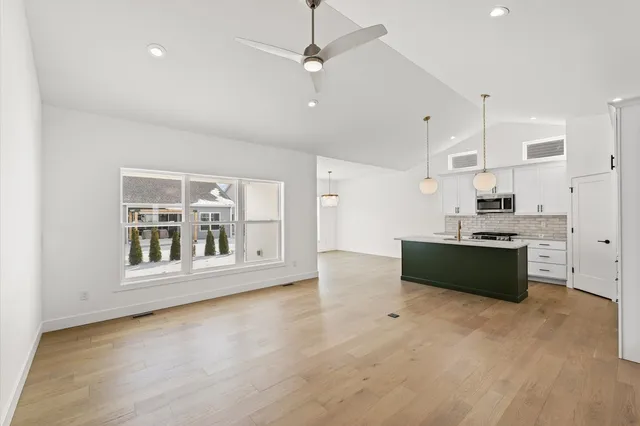 a large kitchen with stainless steel appliances granite countertop a stove a sink and a refrigerator with white cabinets