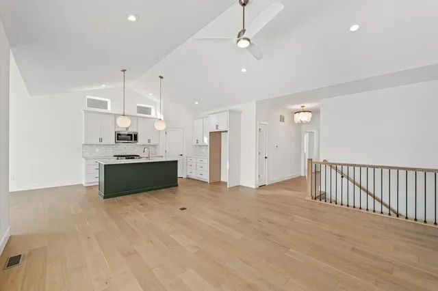 a large white kitchen with kitchen island a sink stainless steel appliances and cabinets