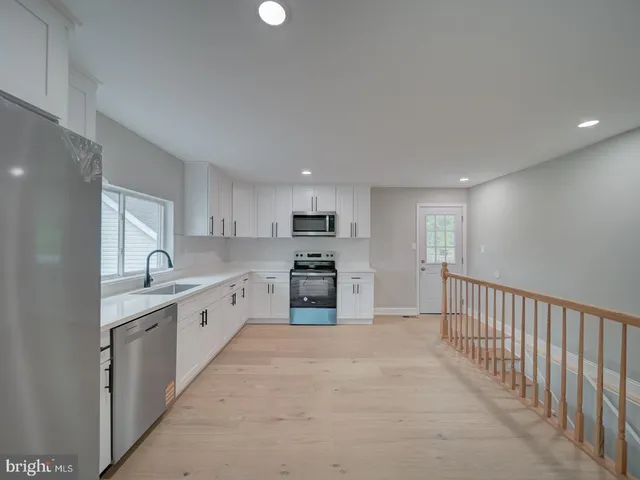 a kitchen that has a lot of white cabinets and stainless steel appliances