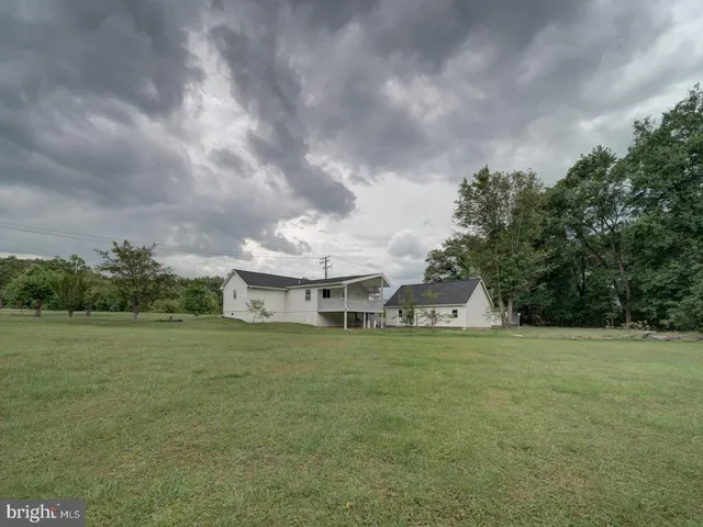 a view of a house with a big yard and large trees