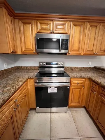 a kitchen with granite countertop a sink and a stove top oven