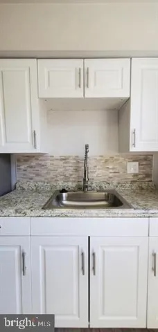 a kitchen with granite countertop a sink a stove and cabinets