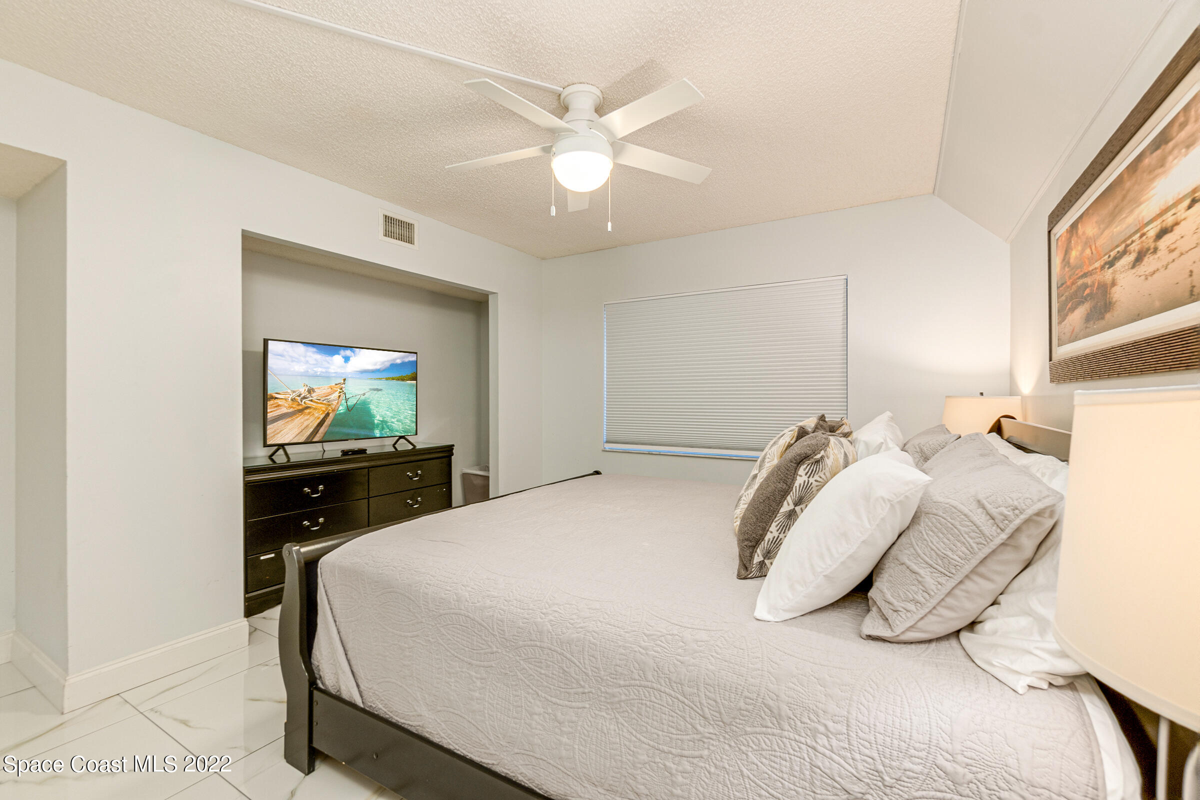 7520 Ridgewood Avenue, Unit 104 Cape Canaveral, FL 32920 - Photo 14 of 35 a bedroom with a bed and a flat screen tv