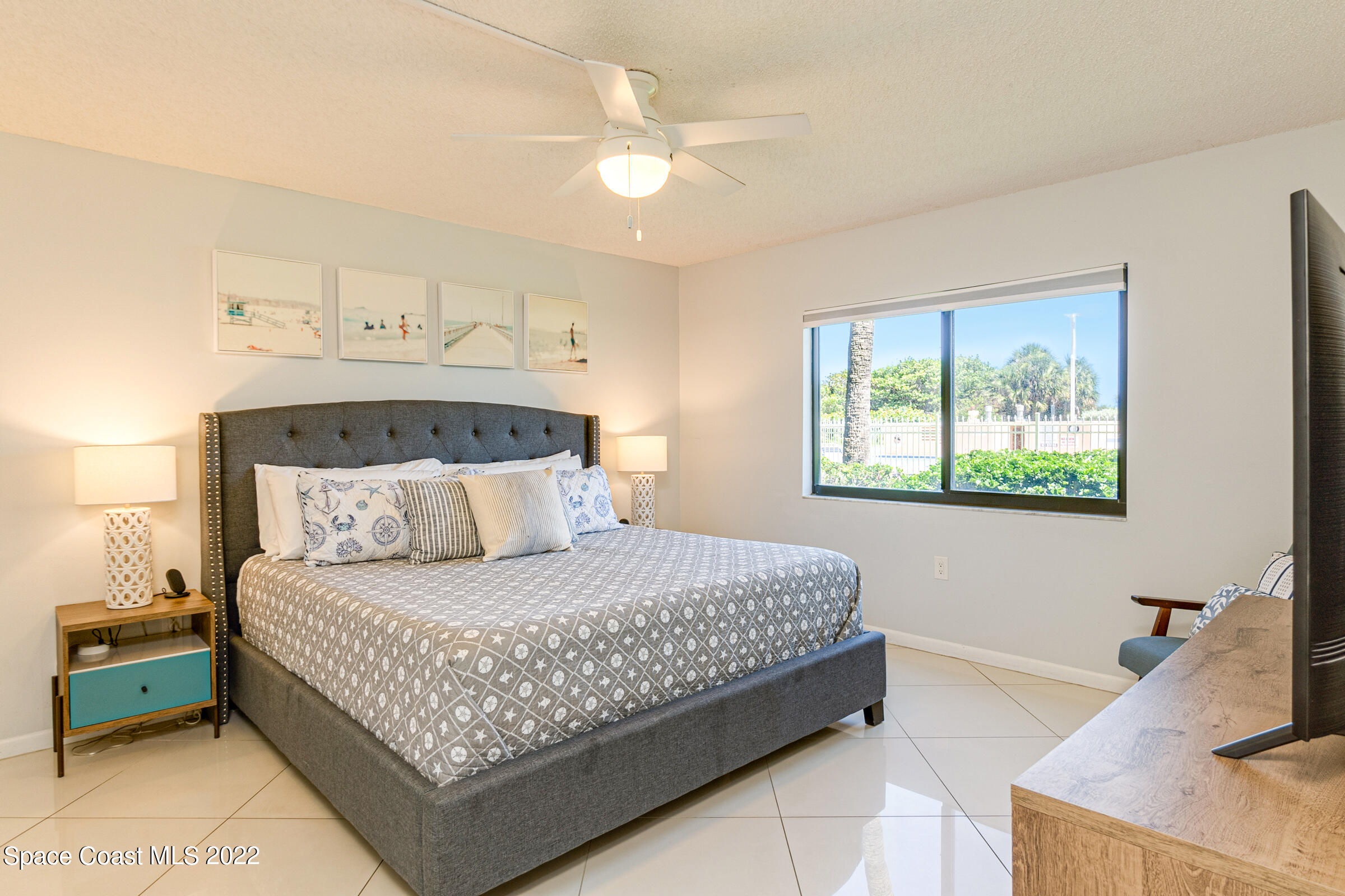 7520 Ridgewood Avenue, Unit 104 Cape Canaveral, FL 32920 - Photo 10 of 35 a bedroom with a bed and a chandelier