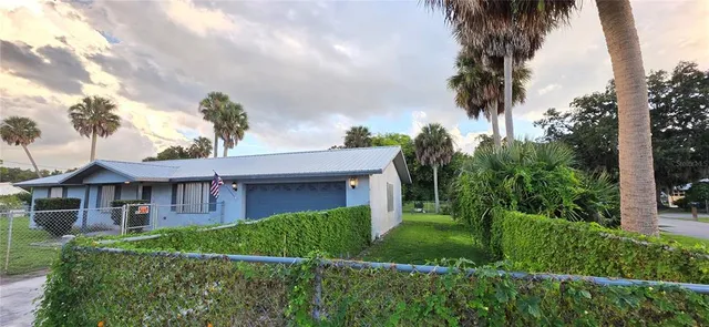 a view of a house with a big yard plants and large trees