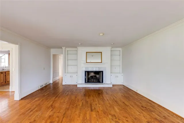 a view of empty room with wooden floor and fireplace