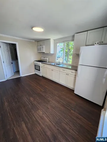 a kitchen with granite countertop white cabinets and white appliances