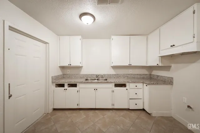 a kitchen with granite countertop a sink a stove and cabinets