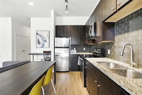 a kitchen with kitchen island granite countertop a sink a counter space appliances and cabinets