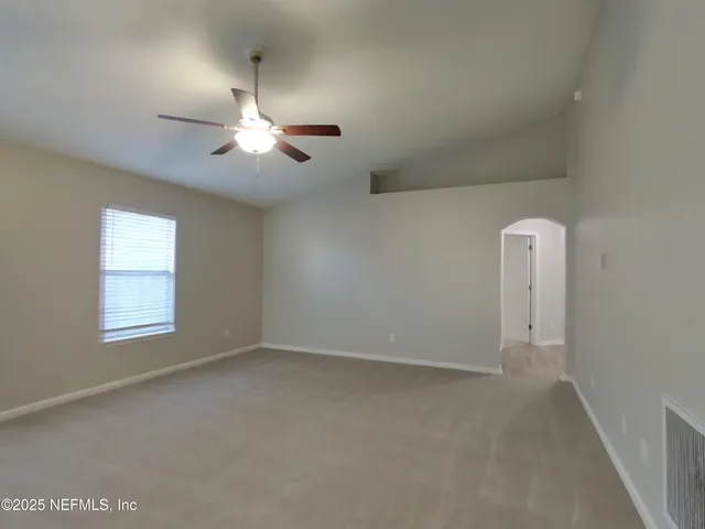 an empty room with windows and fan