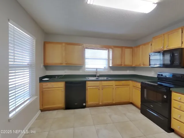 a kitchen with granite countertop cabinets stainless steel appliances a sink and a window
